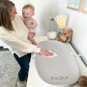 Mother cleaning Evolur Eva changing pad with infant in arm