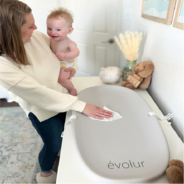 Mother cleaning Evolur Eva changing pad with infant in arm